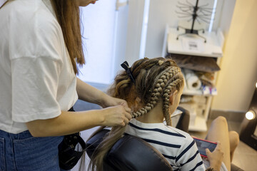 Creating intricate braids in a stylish salon setting during a sunny afternoon