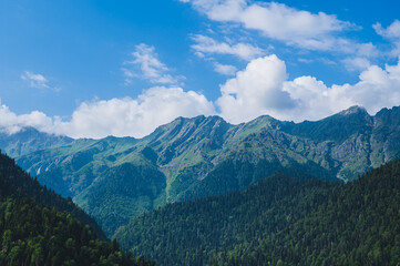 Beautiful Caucasian mountains covered with trees and blue sky with clouds