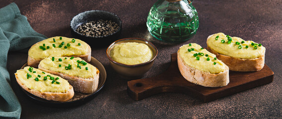 Sandwiches with zucchini and onion spread on ciabatta on a board on a table web banner