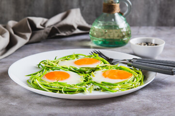 Appetizing zucchini noodle nests with fried eggs on a plate on the table