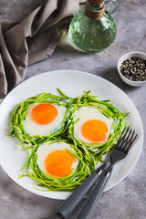 Fried eggs in zucchini noodle nests on a plate on the table vertical view