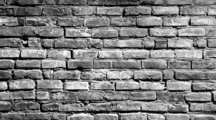 Obraz premium The brick wall features a blend of light and dark shades, showcasing imperfections and unique textures. Natural light emphasizes the contours, creating visual interest in a monochromatic setting.