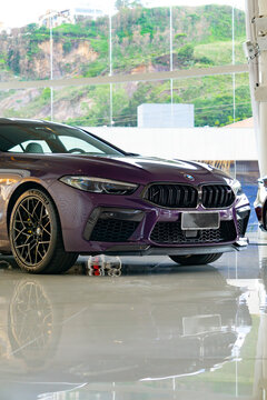 Purple BMW M8 Competition Gran Coupe in a showroom, Low angle view of a luxury performance car


