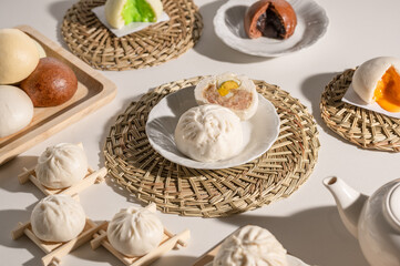 A beautifully arranged display of various steamed buns, showcasing different fillings and colors, on a textured table setting.