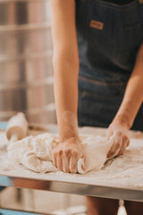 A person kneads dough on a floured surface, showcasing the art of baking and food preparation in a cozy, inviting kitchen environment.