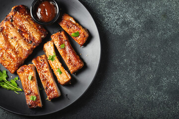 Hot grilled spare ribs from a summer BBQ served on a plate with sauce. Top view. Copy space