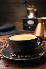Aromatic coffee in cup, beans, cezve and grinder on wooden table, closeup
