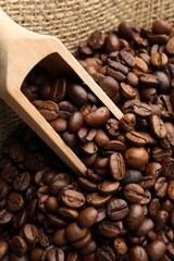 Aromatic coffee beans and scoop in burlap bag, above view