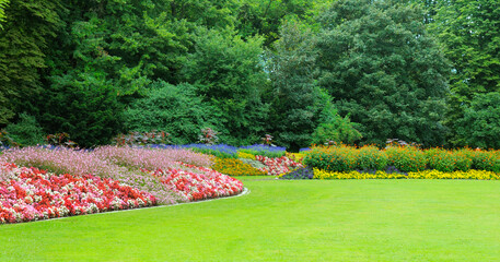 A vibrant park landscape with manicured lawns and flower beds.