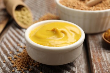 Different types of mustard on wooden table, closeup