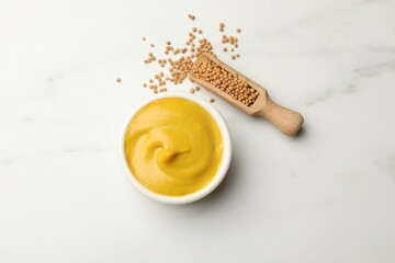 Tasty mustard sauce and dry seeds on white marble table, flat lay