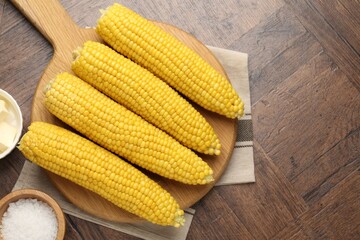 Tasty boiled corncobs, salt and butter on wooden table, flat lay