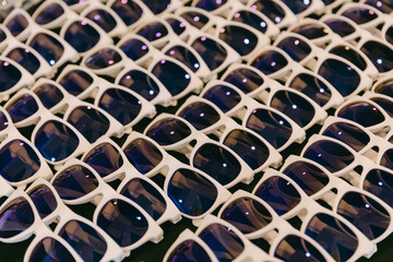 Fototapeta premium Large collection of stylish white sunglasses displayed in a market setting under bright lighting