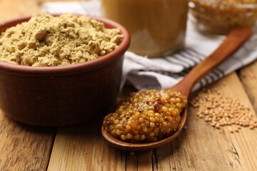 Different types of mustard on wooden table, closeup