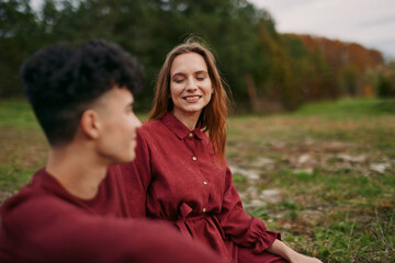 Fototapeta premium A candid outdoor portrait of two young people sharing a genuine moment on a grassy field, conveying authenticity and quiet connection through natural expressions, relaxed posture and soft autumn