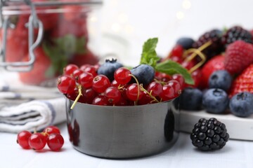 Ripe red currants, blueberries in scoop on white tiled table, closeup