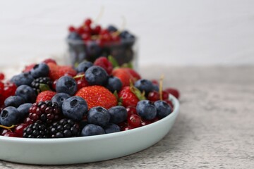 Different ripe berries on light grey textured table, closeup. Space for text