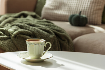 Cozy Autumn Scene with Green Cup of Coffee and Sofa Decor