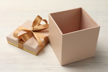 Open gift box with beautiful lid on white wooden table