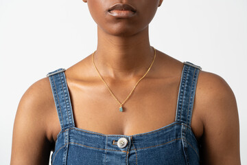 Close-up of woman wearing gold necklace with green gemstone pendant