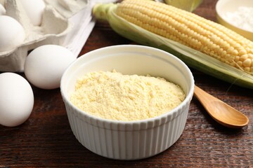 Different ingredients for corn bread. Corn flour, cob and eggs on wooden table, closeup
