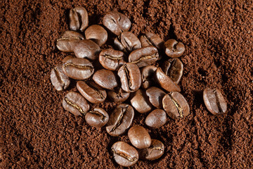 Top view of scattered coffee beans on a background of ground coffee