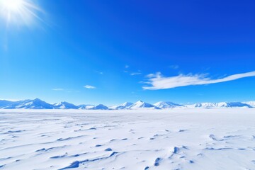 Vast snow covered landscape under bright blue sky mountains