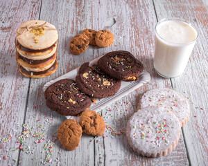 Assorted cookies with chocolate and sugar, decorated with sprinkles and served with a glass of milk, sweet dessert for holidays and celebrations