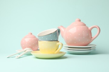 Beautiful ceramic tea set for children on turquoise background, closeup