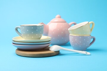 Beautiful ceramic tea set for children on light blue background, closeup