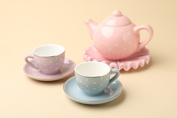 Beautiful ceramic tea set for children on beige background, closeup