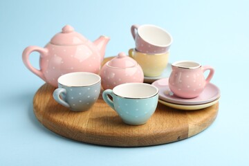 Beautiful ceramic tea set for children on light blue background, closeup