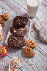 Assorted cookies with chocolate and sugar, decorated with sprinkles and served with a glass of milk, sweet dessert for holidays and celebrations
