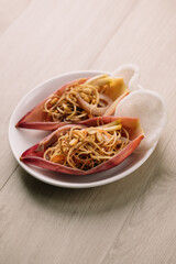 A plate of delicious noodles served in edible flower-shaped cups, accompanied by crispy crackers, showcasing a unique culinary presentation.
