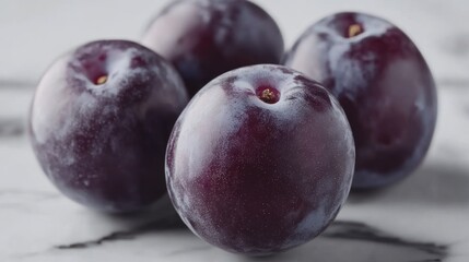 Obraz premium Close-up of Four Ripe Plums on Marble Surface