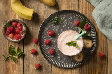 Refreshing banana raspberry smoothie with fresh mint for healthy living and summer enjoyment. Top view flat lay background.