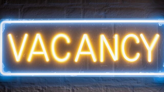 Neon vacancy sign glowing on brick wall. Illuminated hotel or motel availability indicator. Bright yellow letters in blue frame. Hospitality industry concept.