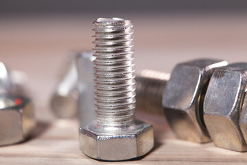 Metal bolts and nuts on a wooden table. Close-up.
