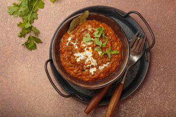 Dal makhani with cream and coriander leaves served in rustic bowl, accompanied by spices such as turmeric, cinnamon, and star anise, authentic Indian dish