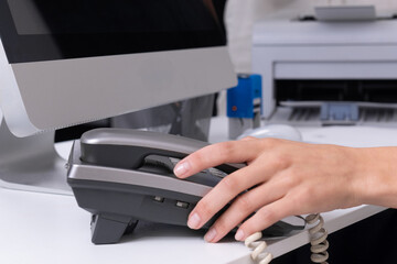 Office scene with a secretary using a telephone while working at a desk in a modern workspace