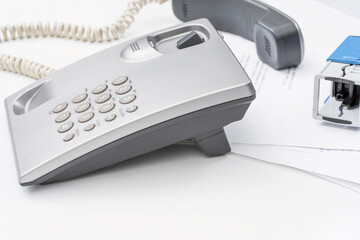 Office secretary using a telephone while managing paperwork at a desk in a busy work environment