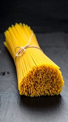 A bundle of yellow spaghetti on a dark surface