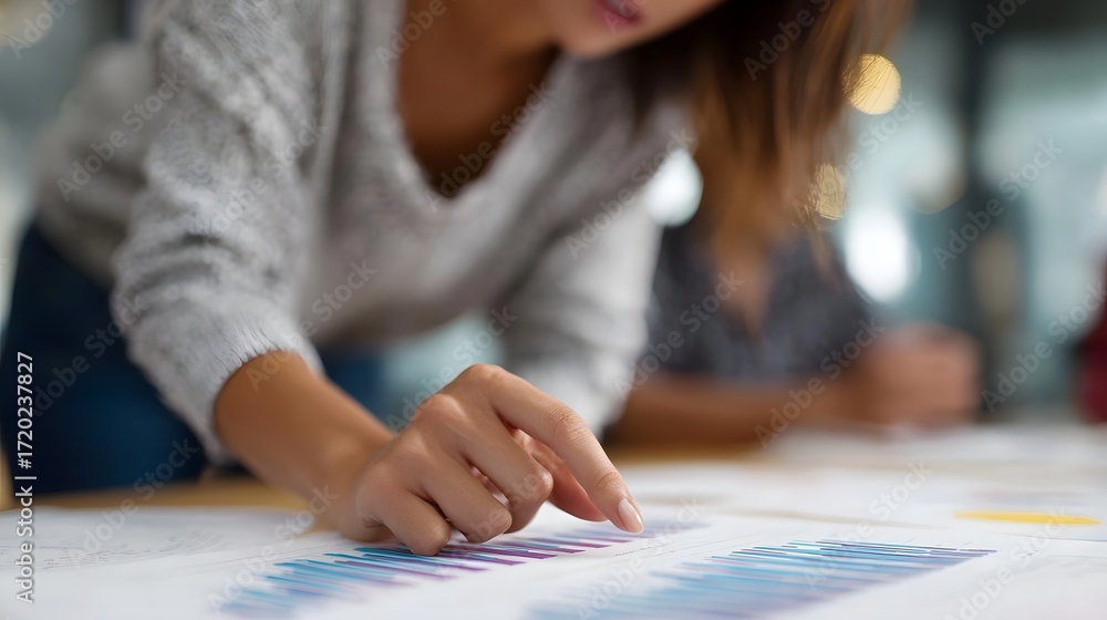 Poster woman s hand points to bar graph on paper in collaborative office symbolizing data analysis and plan