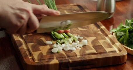 Of fresh herbs being chopped on a wooden cutting board over a wooden table. Close-up 4K shot of a chef chopping fresh spring onions, parsley, and dill on a wooden cutting board placed on a rustic - Powered by Adobe