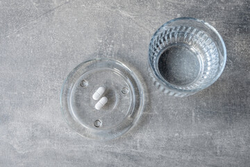 Obraz premium White pill and glass with water stay on the table.