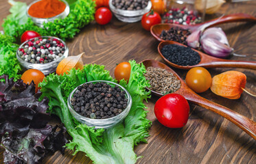 Arrangement of bright spices and vegetables red tomatoes, garlic, physalis on textured wooden board.