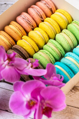 Lots of colorful macaroons in the box. Blue, green, yellow, brown color desserts on a treat box