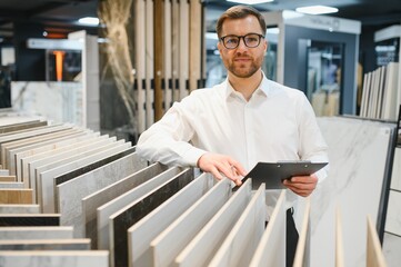 Salesman showing ceramic tiles to customer in hardware store