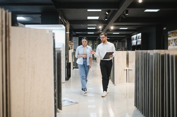Salesman showing ceramic tiles to customer in showroom