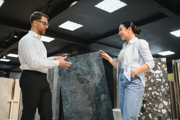 Naklejka premium Shop assistant showing ceramic tile to woman in store